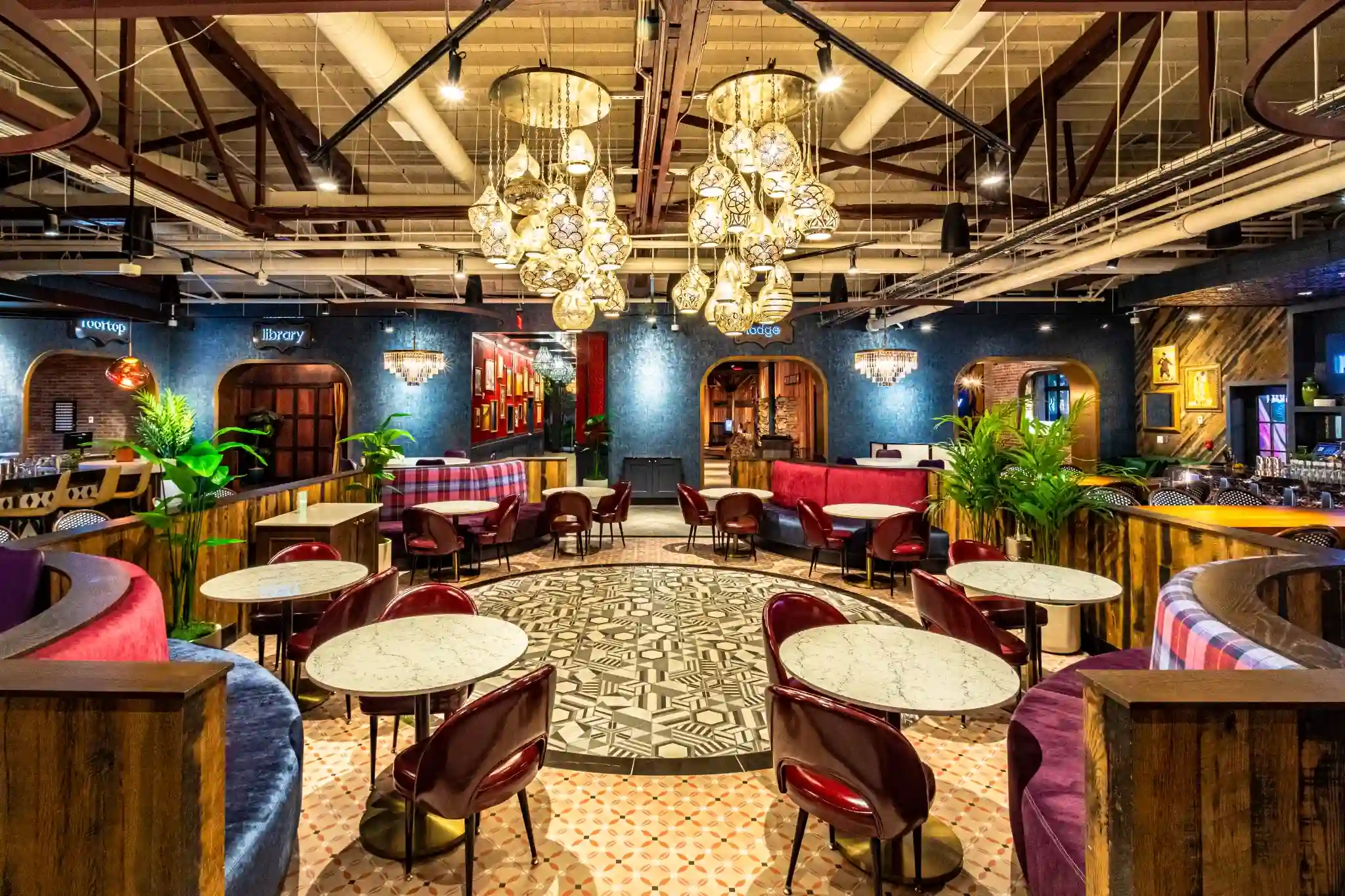 Main dining room at Puttery Miami with chandeliers, curved banquettes, marble tables and colorful seating.
