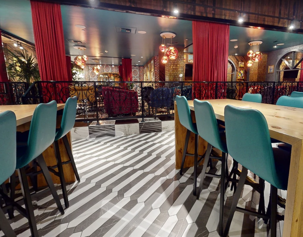 High-top tables and flexible group seating at Puttery Minneapolis, framed by red curtains and decorative railings.