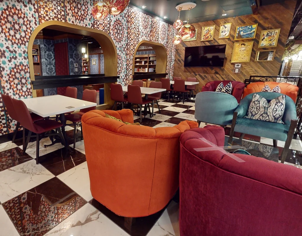 Colorful lounge and dining area at Puttery Minneapolis with sofas, tables, patterned walls and a large TV.
