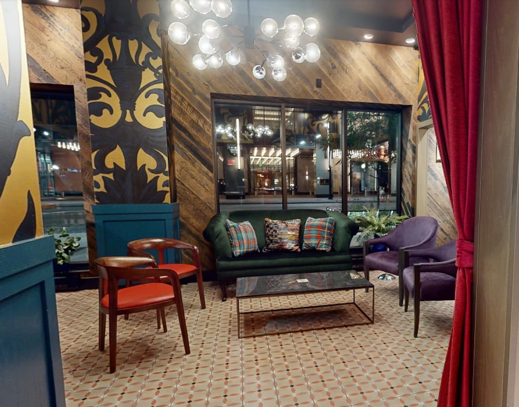 Intimate window lounge at Puttery Minneapolis with a green sofa, colorful chairs and downtown street views.