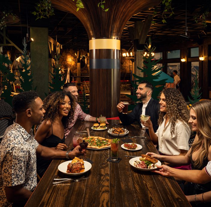 friends enjoying craft cocktails and shareable food at a high top table