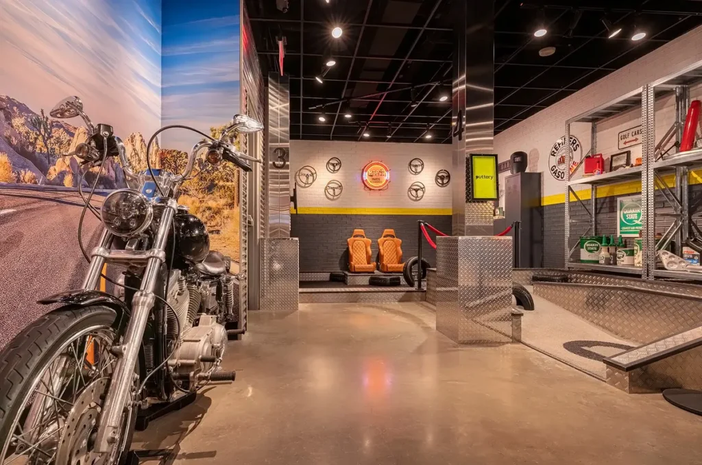 Motorcycle display on the Garage Course at Puttery Pittsburgh with desert mural, industrial columns and automotive-themed mini golf lanes.