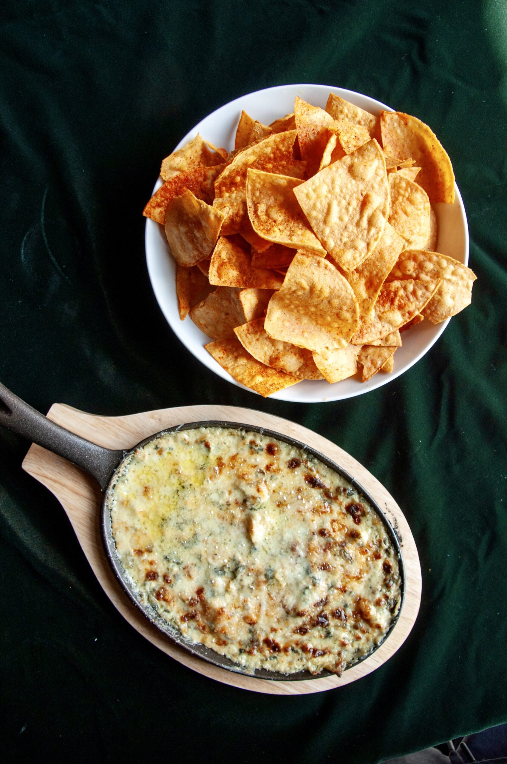Close-up of a tortilla chip being dipped into a creamy, spinach-packed dip at Puttery.