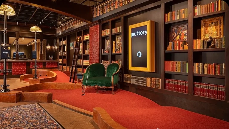 Library-themed indoor mini golf course at Puttery Chicago with bookshelves, vintage seating and red-carpeted putting greens.