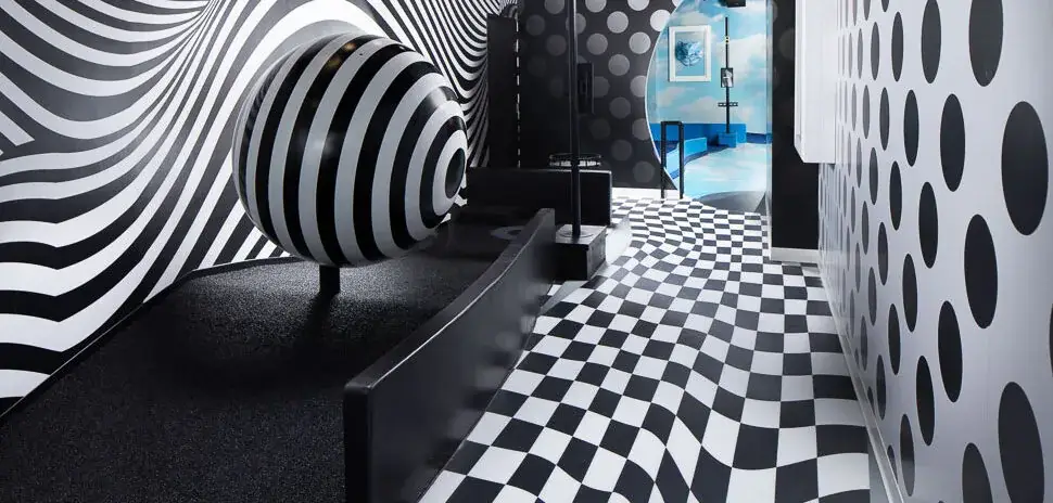 Puttery Dallas Illusion Course - Puttery Black-and-white optical illusion mini golf hole with a striped sphere and warped checkerboard floor at Puttery Dallas.