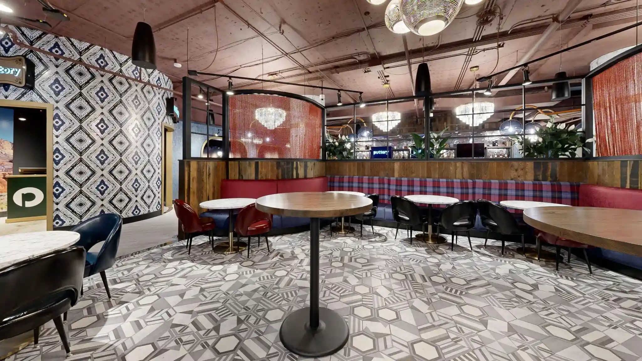 Banquette dining area at Puttery Kansas City with geometric floors, round tables and crystal chandeliers.