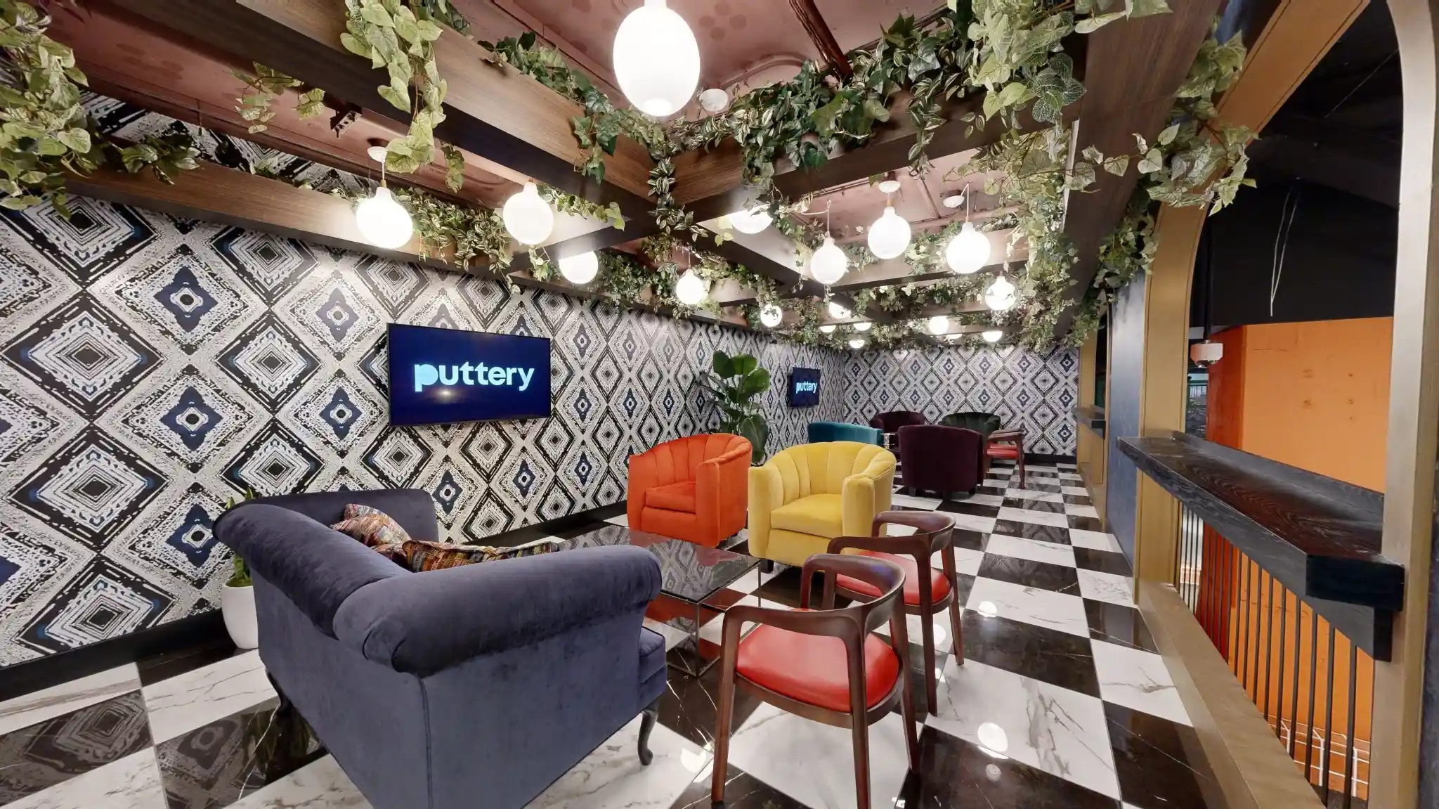Puttery Kansas City lounge with patterned walls, hanging greenery, globe lights and colorful seating.