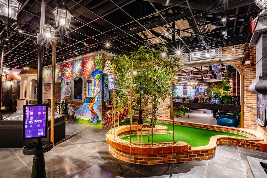 Graffiti-inspired indoor mini golf course at Puttery Miami with brick walls, murals, greenery and putting turf.