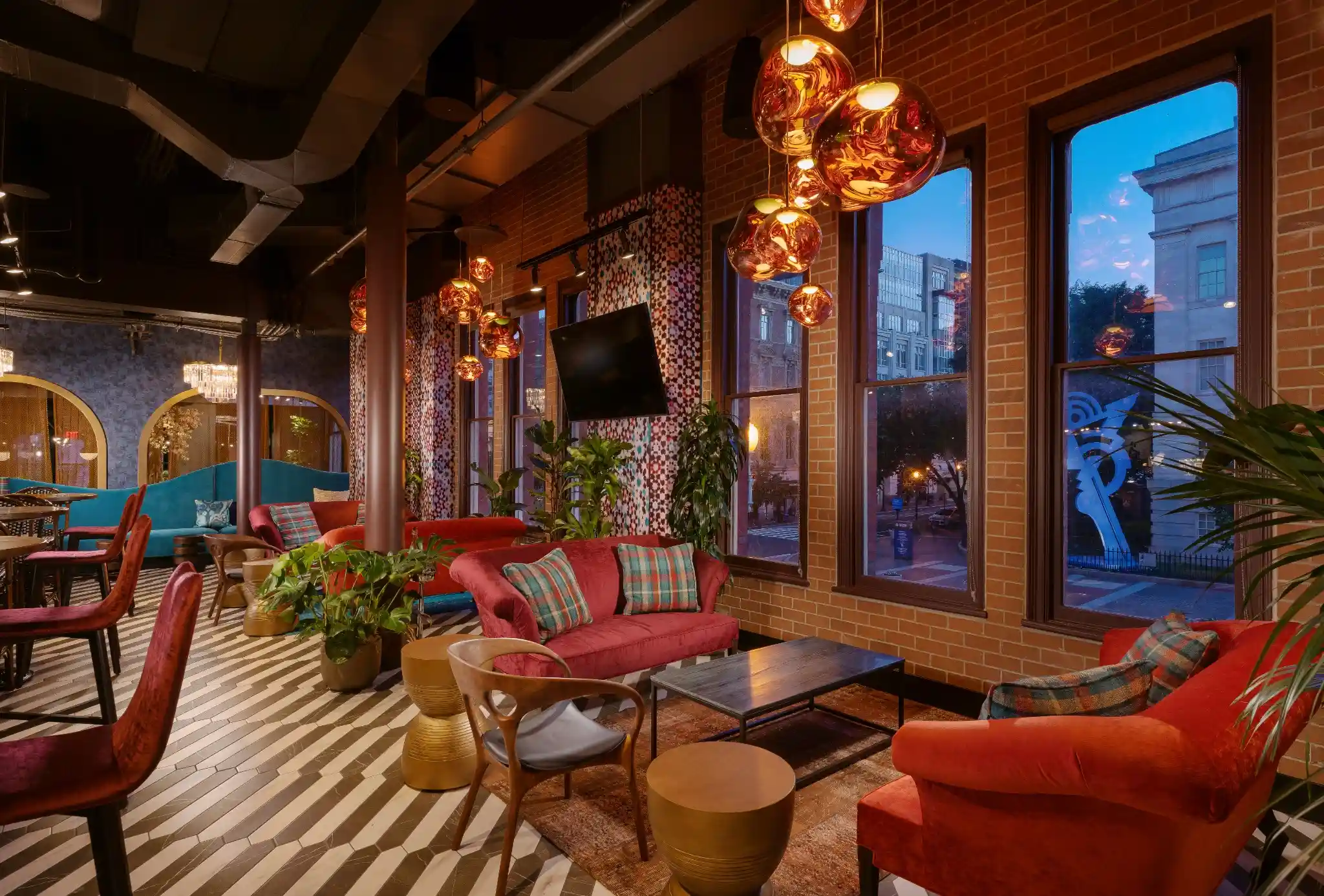 Cocktail lounge at Puttery Washington DC with red sofas, copper pendant lights and striped floors.