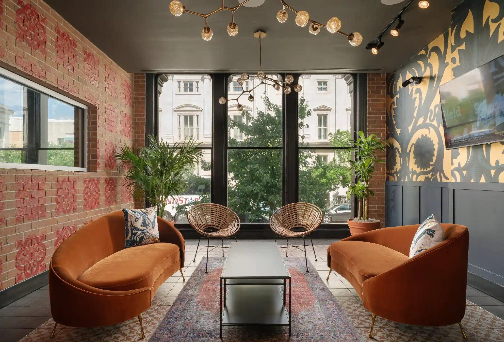 Private lounge at Puttery Washington DC with orange sofas, woven chairs and large windows.