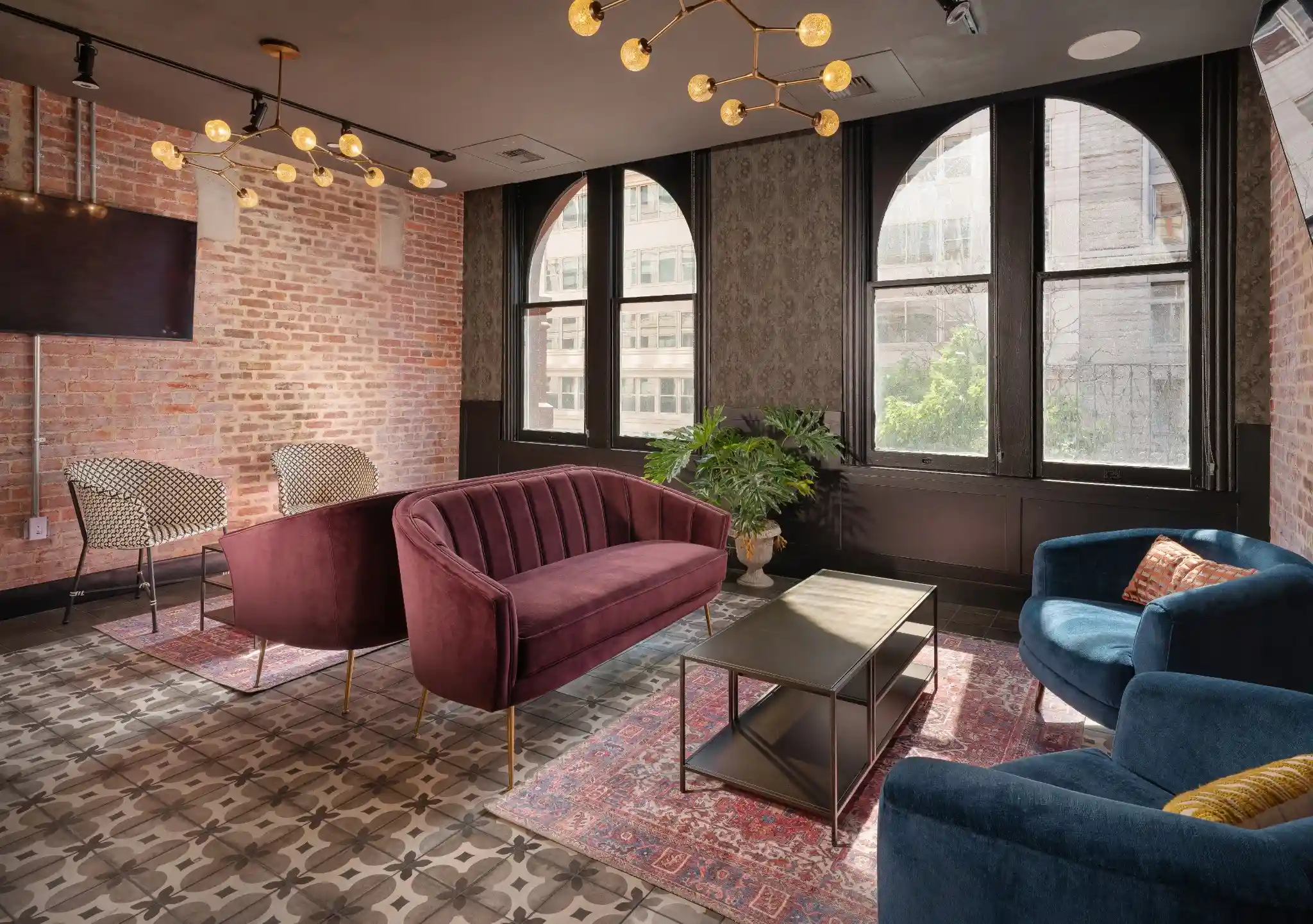 Lounge at Puttery Washington DC with a purple sofa, blue chair, arched windows and patterned tile flooring.