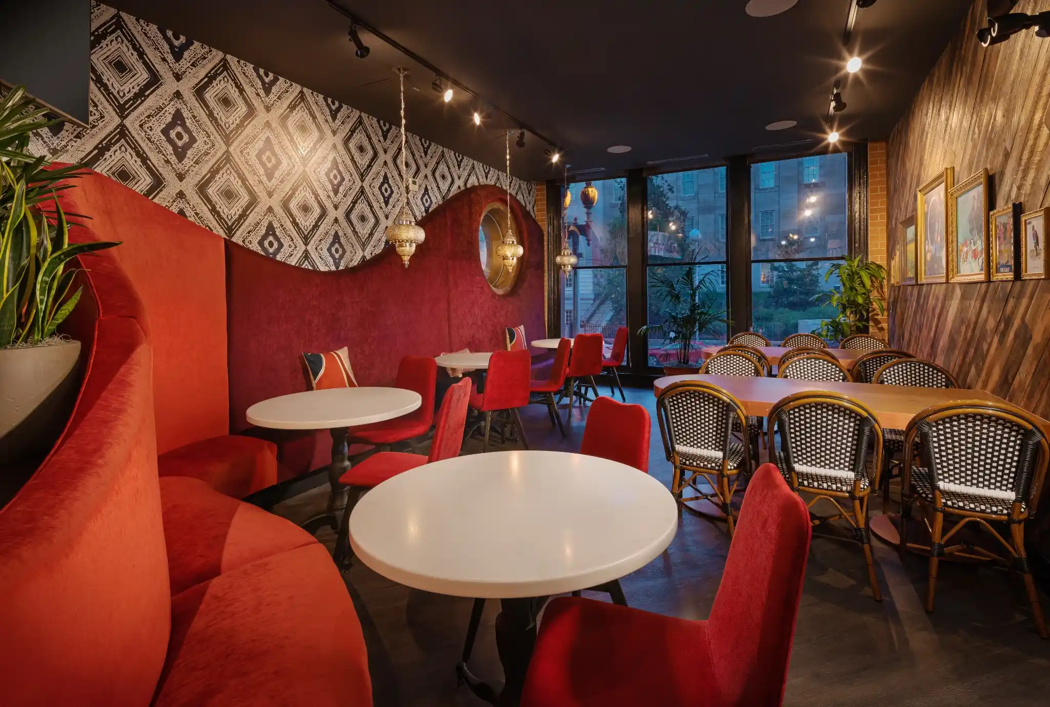 Red banquette dining area at Puttery Washington DC with white tables, red chairs and framed artwork.