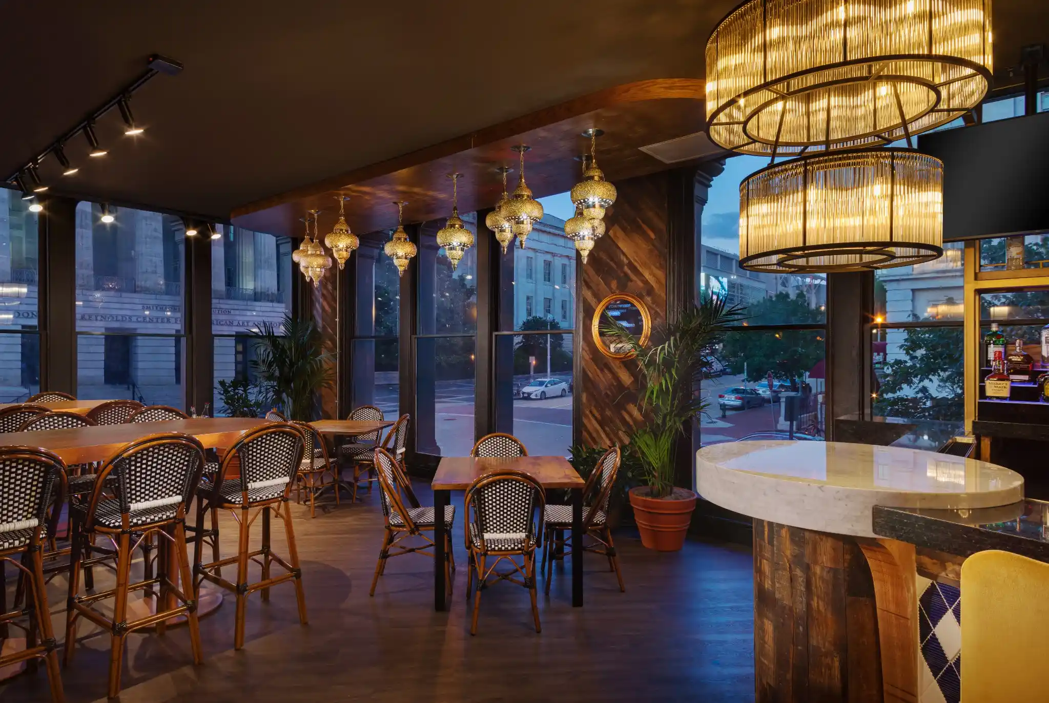 Window dining area at Puttery Washington DC with wood tables, woven chairs and statement lighting.