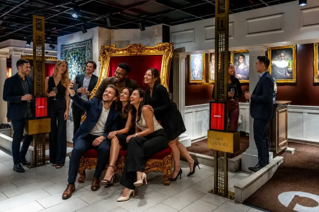 Coworkers laugh and pose for a group selfie during a team-building event at Puttery New York City.