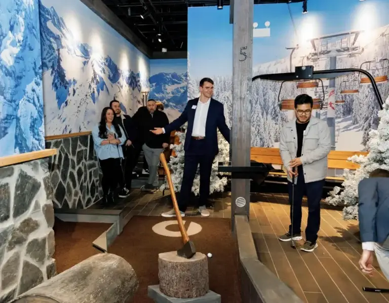 Coworkers play mini golf together during a corporate team-building event on the Lodge course at Puttery New York City.