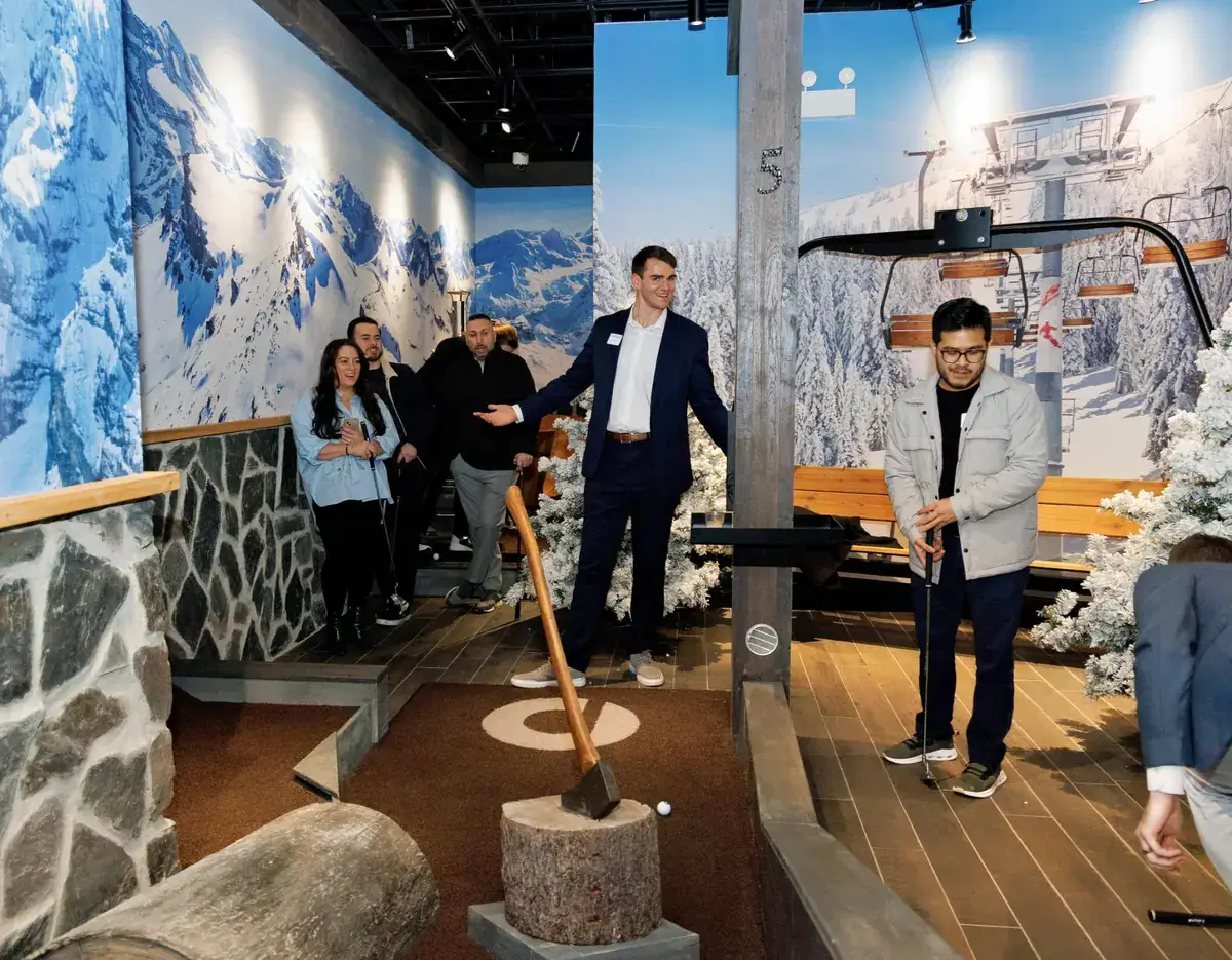 Coworkers play mini golf together during a corporate team-building event on the Lodge course at Puttery New York City.