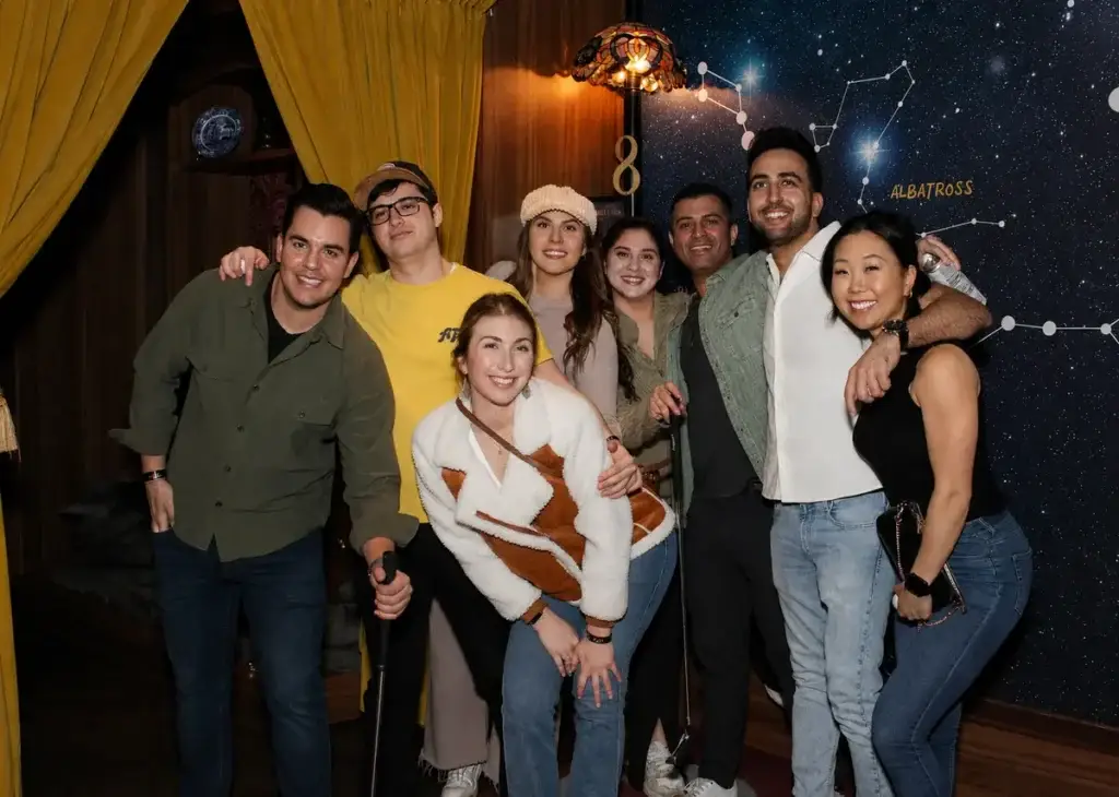 Coworkers pose together during a Puttery team-building event on an immersive indoor mini golf course.