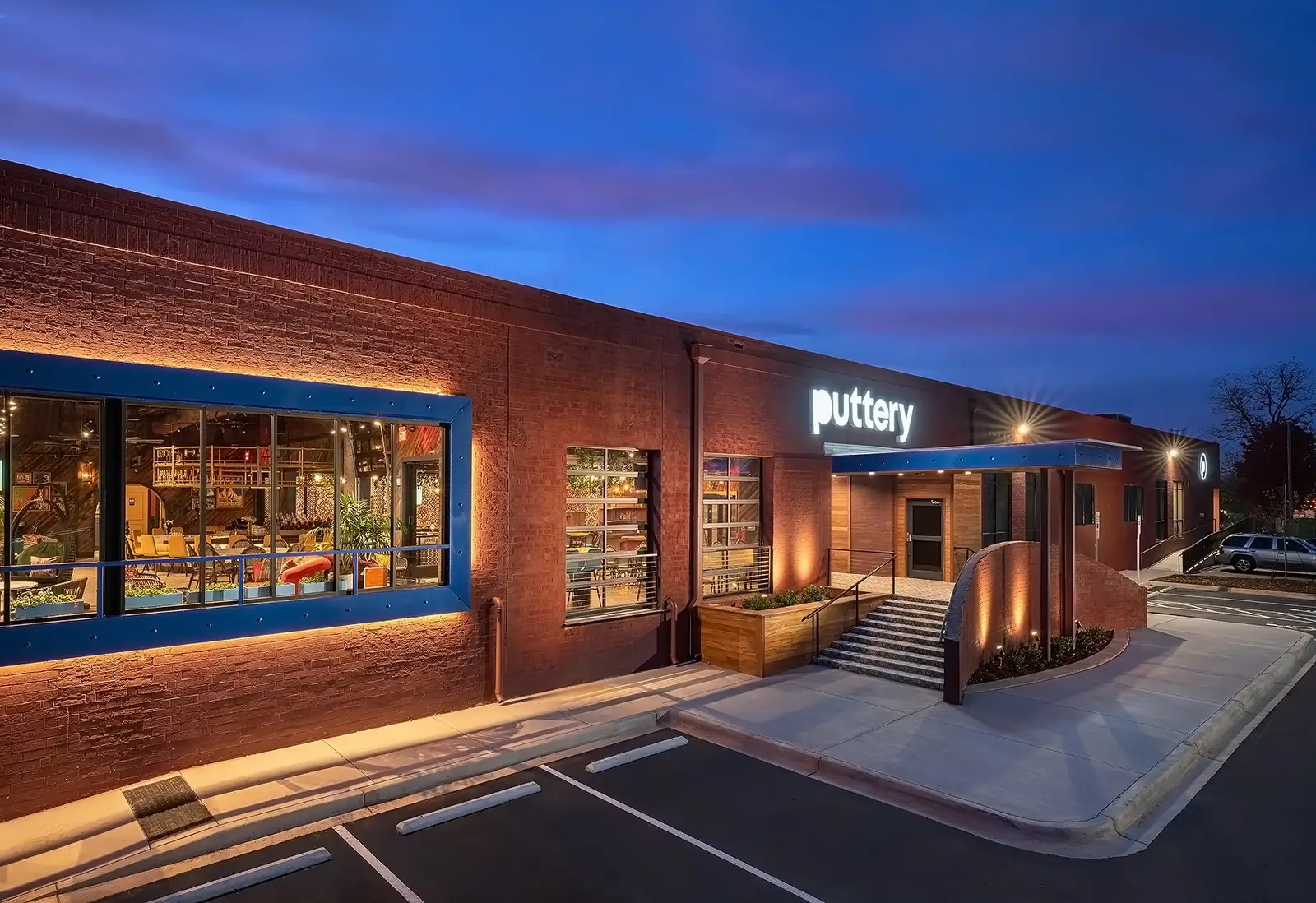 Puttery Charlotte exterior at dusk with illuminated signage and warm interior lighting.