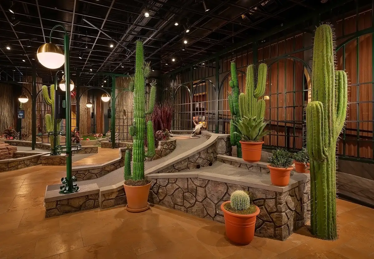 Desert-inspired Conservatory Course at Puttery Charlotte with towering cacti, stone pathways and immersive indoor mini golf holes.