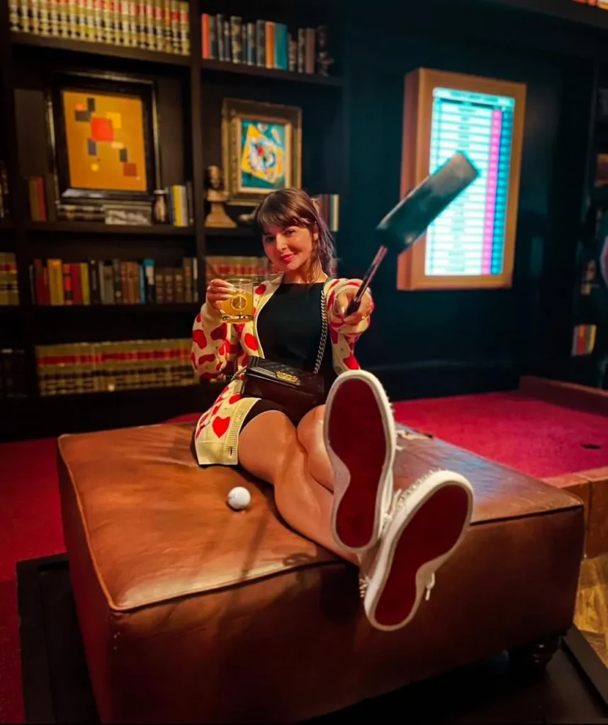 Guest enjoying a cocktail and mini golf on the Library course at Puttery Dallas in The Colony at Grandscape.