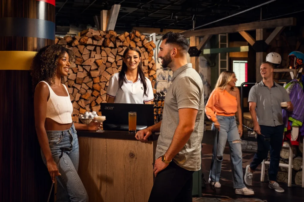 Guests checking in with a staff member at a guest services desk inside a lodge-themed area at Puttery.