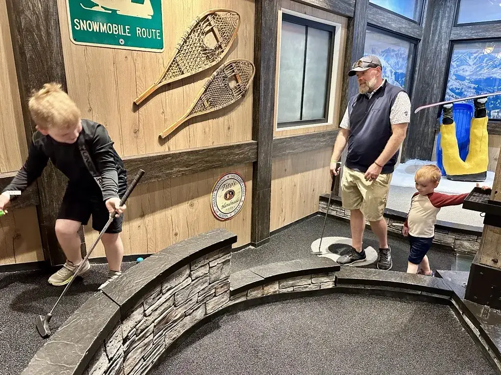 Dad and two young boys playing the ski themed Lodge course at Puttery