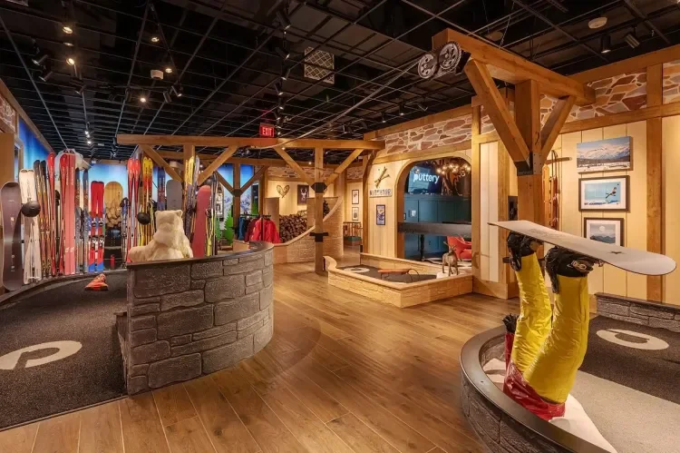 Lodge-themed mini golf course at Puttery Miami featuring wood beams, ski décor, warm lighting and immersive putting lanes.