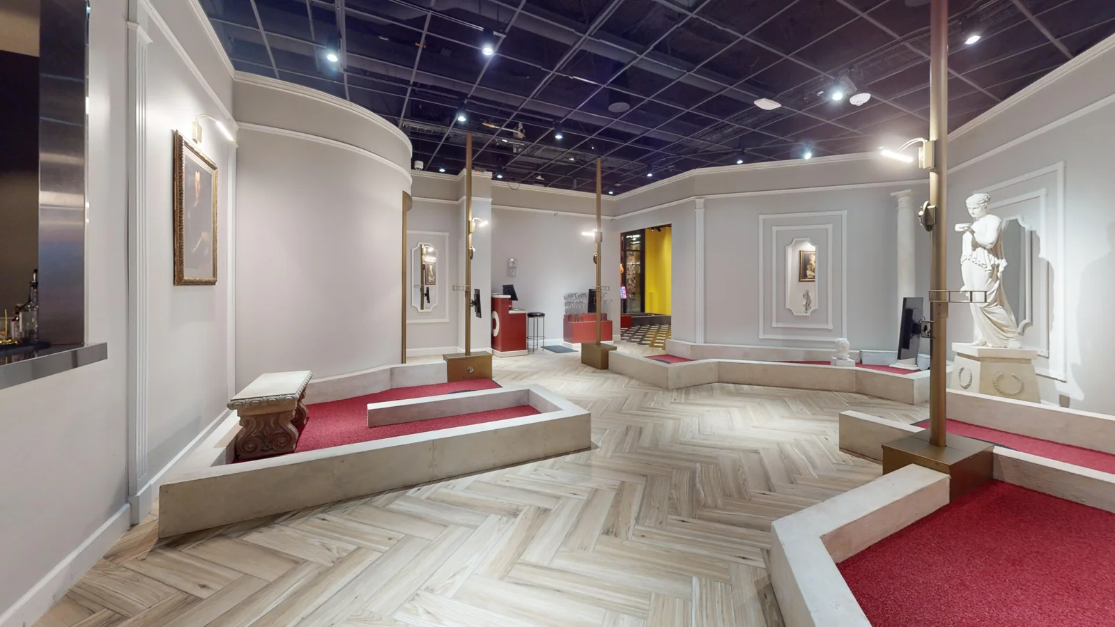 Classical art-themed indoor mini golf course at Puttery Minneapolis with statues, framed artwork and red putting greens.