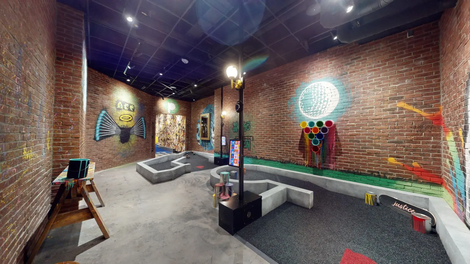 Graffiti-inspired indoor mini golf course at Puttery Minneapolis with exposed brick walls, colorful murals and sculptural obstacles.