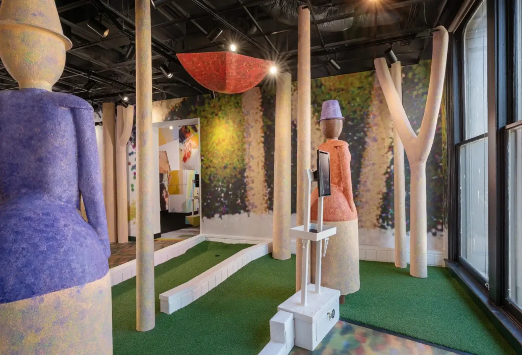Oversized abstract figures and trees surrounding a mini golf hole at Puttery Washington DC.