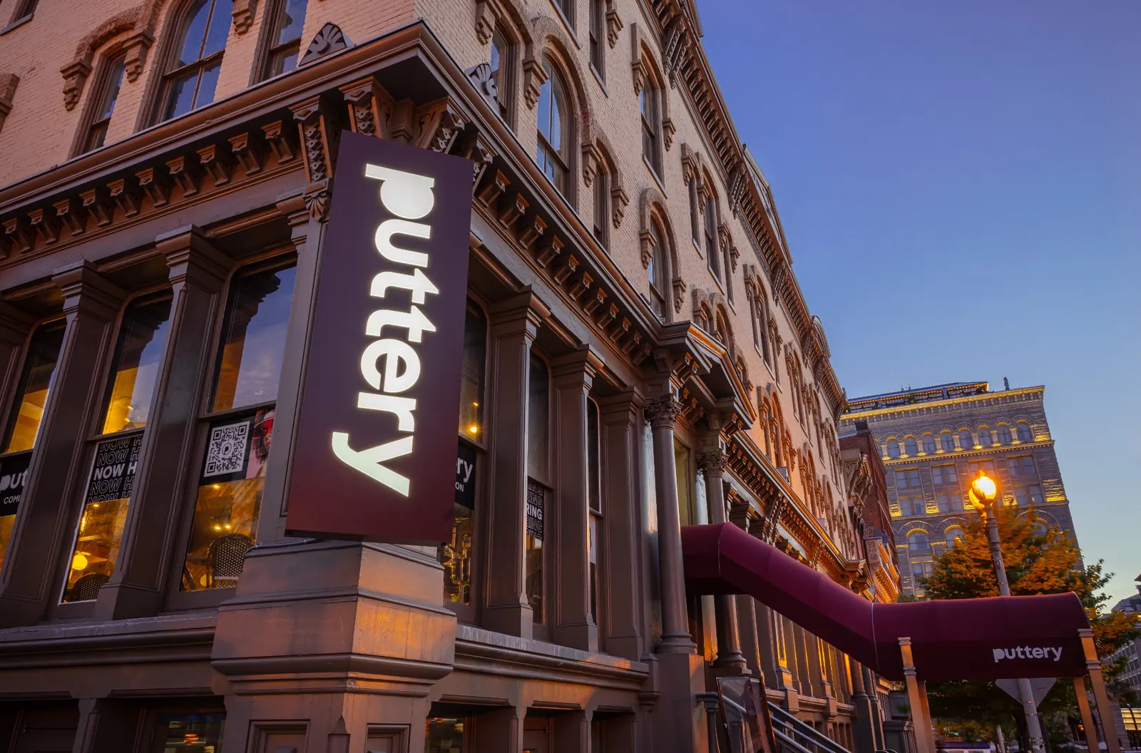 Illuminated Puttery sign and entrance awning on the exterior of Puttery Washington D.C. at dusk.