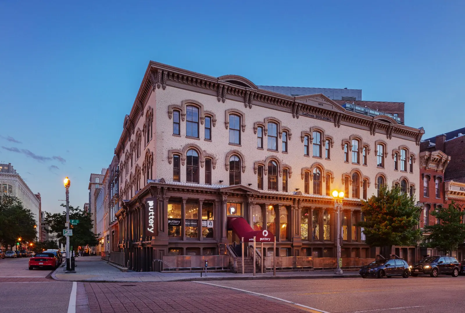 Exterior of Puttery Washington D.C. at dusk in a historic corner building with illuminated signage and warm interior lighting.