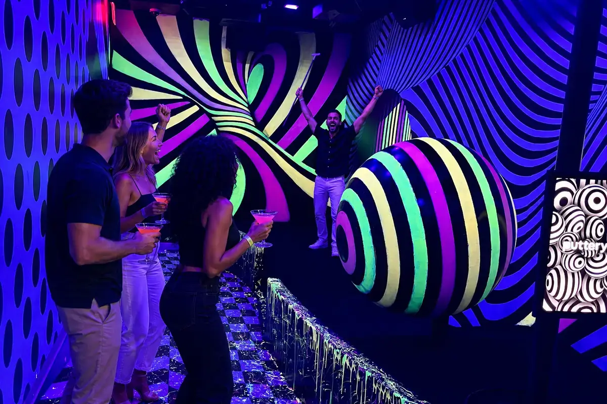 Friends celebrate a hole-in-one with cocktails on the neon Illusion mini golf course at Puttery Dallas in Grandscape, The Colony, Texas.