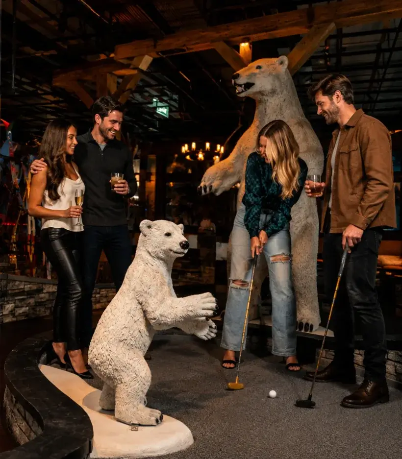 Adults enjoying cocktails and mini golf at Puttery at night