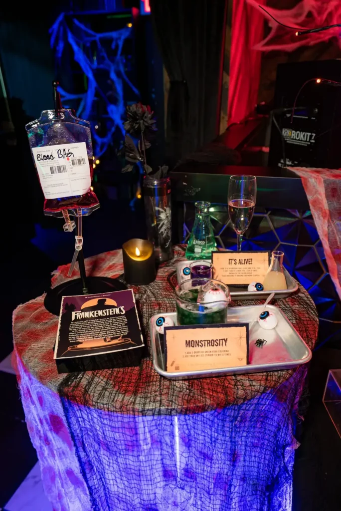 Blood Bag and Monstrosity Cocktails at Frankenstein’s Lab - Puttery Blood Bag, green Monstrosity cocktail and It’s Alive lab setup displayed with beakers, eyeball props and surgical trays at Puttery NYC.