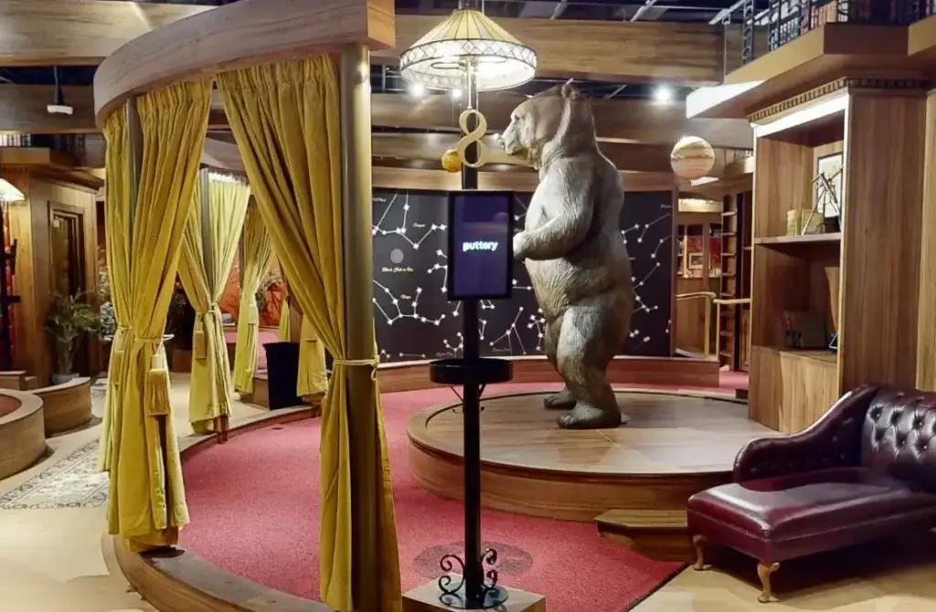 Rotunda area on the Library Course at Puttery Houston with a standing bear statue, gold curtains, a leather sofa, and a constellation-themed room in the background.