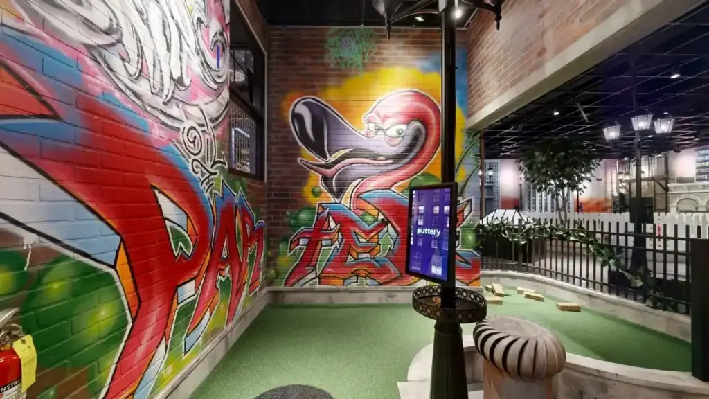 Street art-inspired rooftop mini golf hole with colorful graffiti mural and green turf at Puttery Miami.