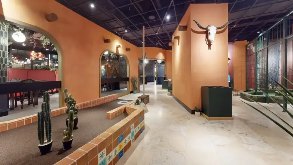 Desert-inspired section of the Conservatory Course at Puttery Minneapolis with cacti, terracotta walls and tiled course borders.