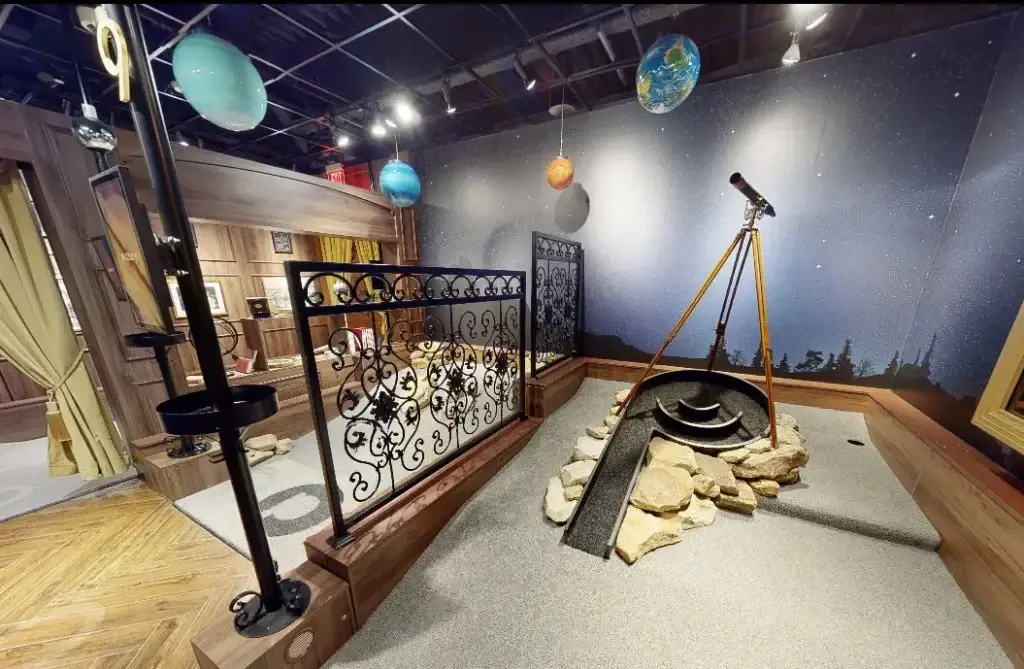 Observatory-themed hole on the Library Course at Puttery Pittsburgh with a telescope, hanging planets, starry backdrop, and rock details.