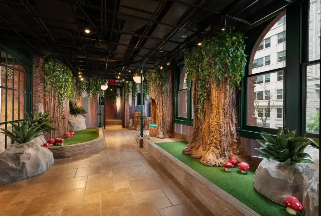 Forest-inspired section of the Conservatory Course at Puttery Washington DC with oversized tree trunks, ivy and red mushroom details.